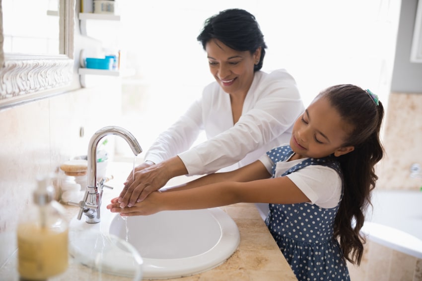 Mom and daughter washing hands in lukewarm water