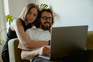Couple together on laptop searching whether or not you need a recirculating pump for your tankless water heater.